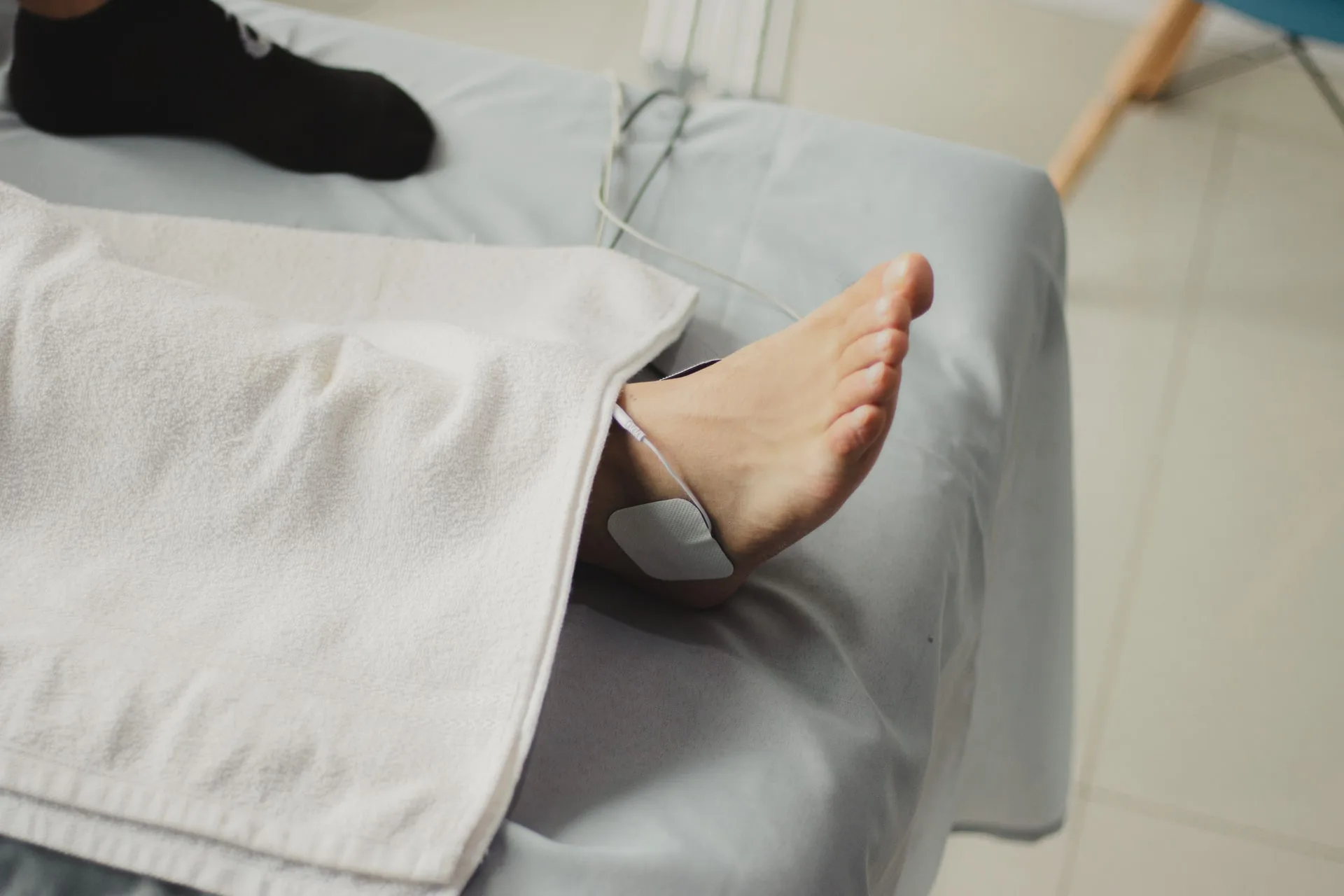 Électrode d'électrostimulation posée sur la cheville d'un patient allongé