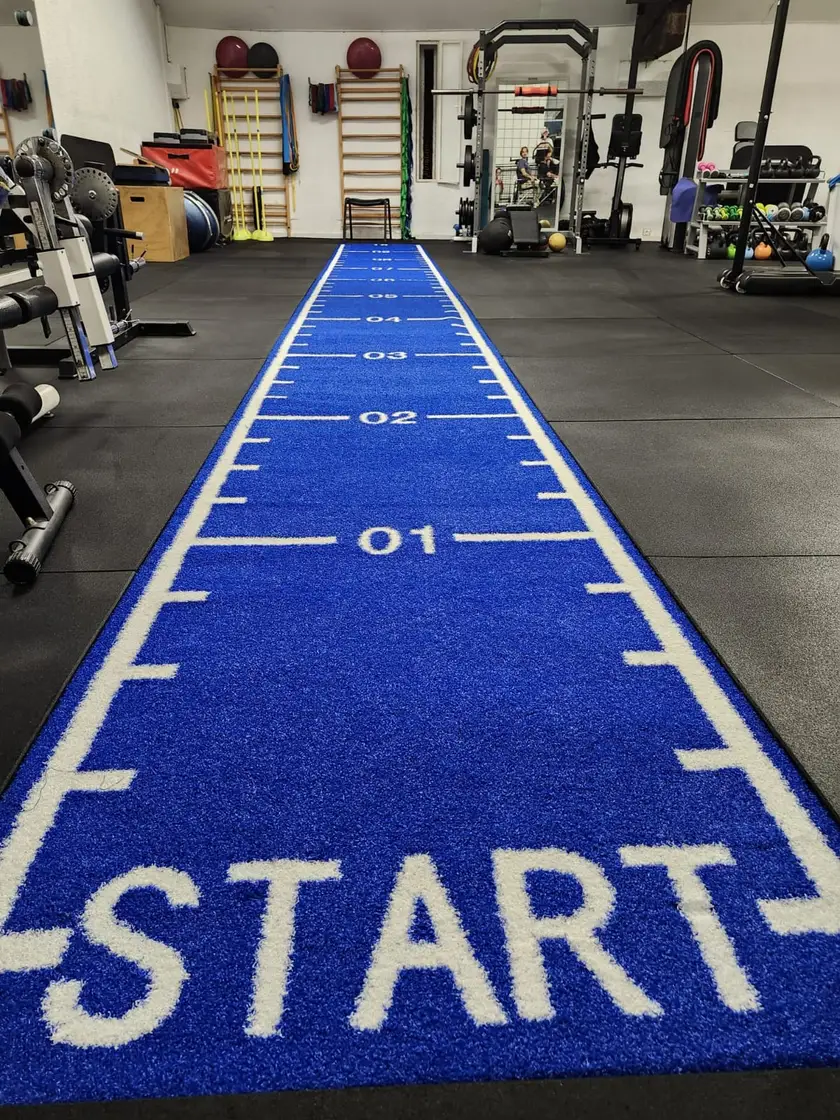 Piste de sprint graduée du plateau technique, bordée des postes de musculation