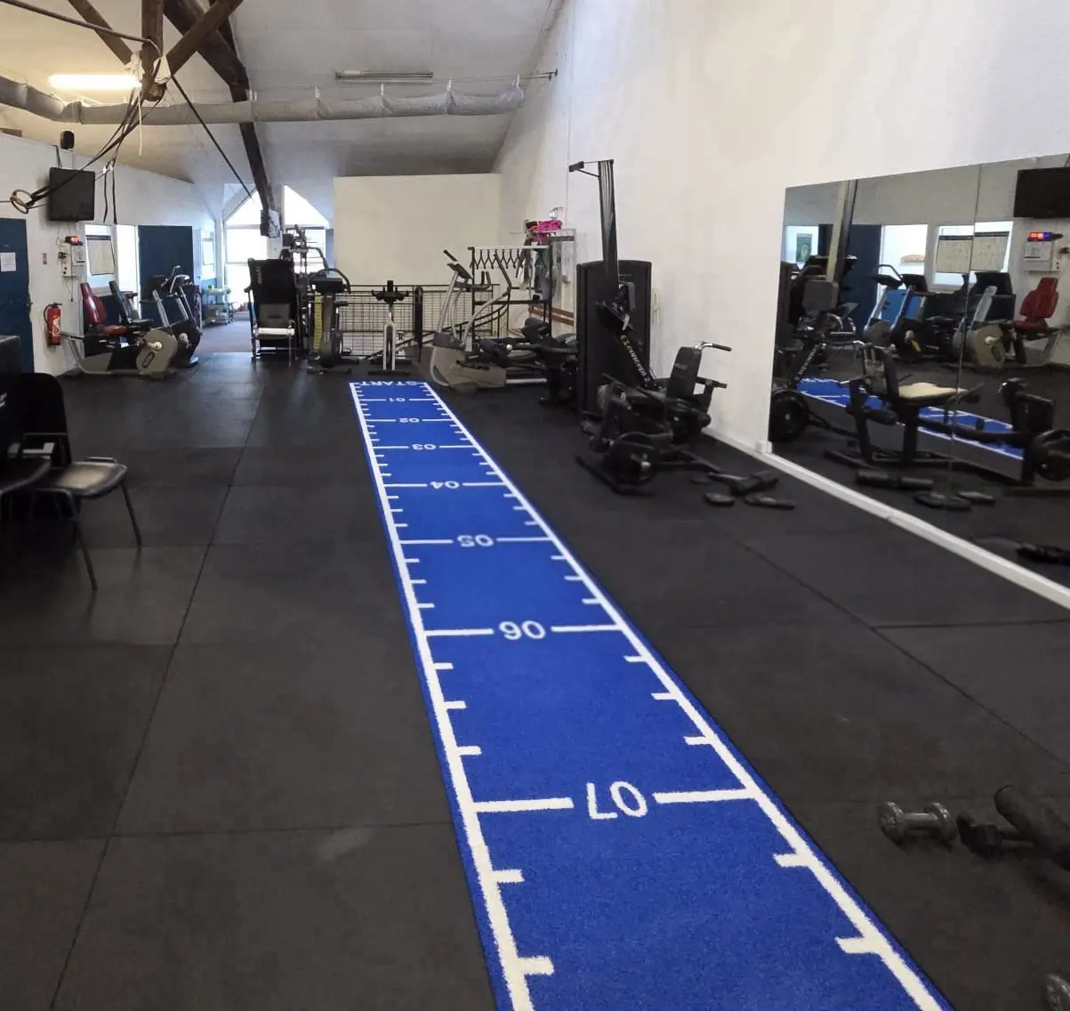 Piste de sprint graduée du plateau technique, bordée des postes de cardio et de musculation